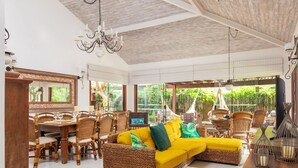 A spacious indoor area with a large wicker sofa, dining table, and chairs. - Bz37 Casa com Piscina a 200M da praia (Buzios)