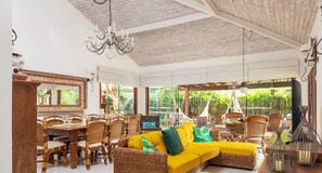 Un espacio interior amplio con un sofá grande de mimbre, una mesa de comedor y sillas.
