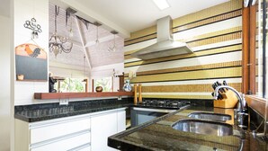 A kitchen with a stove, sink, and a backsplash with yellow and white tiles. - Bz37 Casa com Piscina a 200M da praia (Buzios)