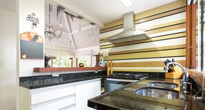 Cocina con estufa, lavamanos y salpicadero de azulejos amarillos y blancos.