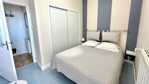 Een slaapkamer met een bed, een kledingkast, een radiator en een deur naar een badkamer.
