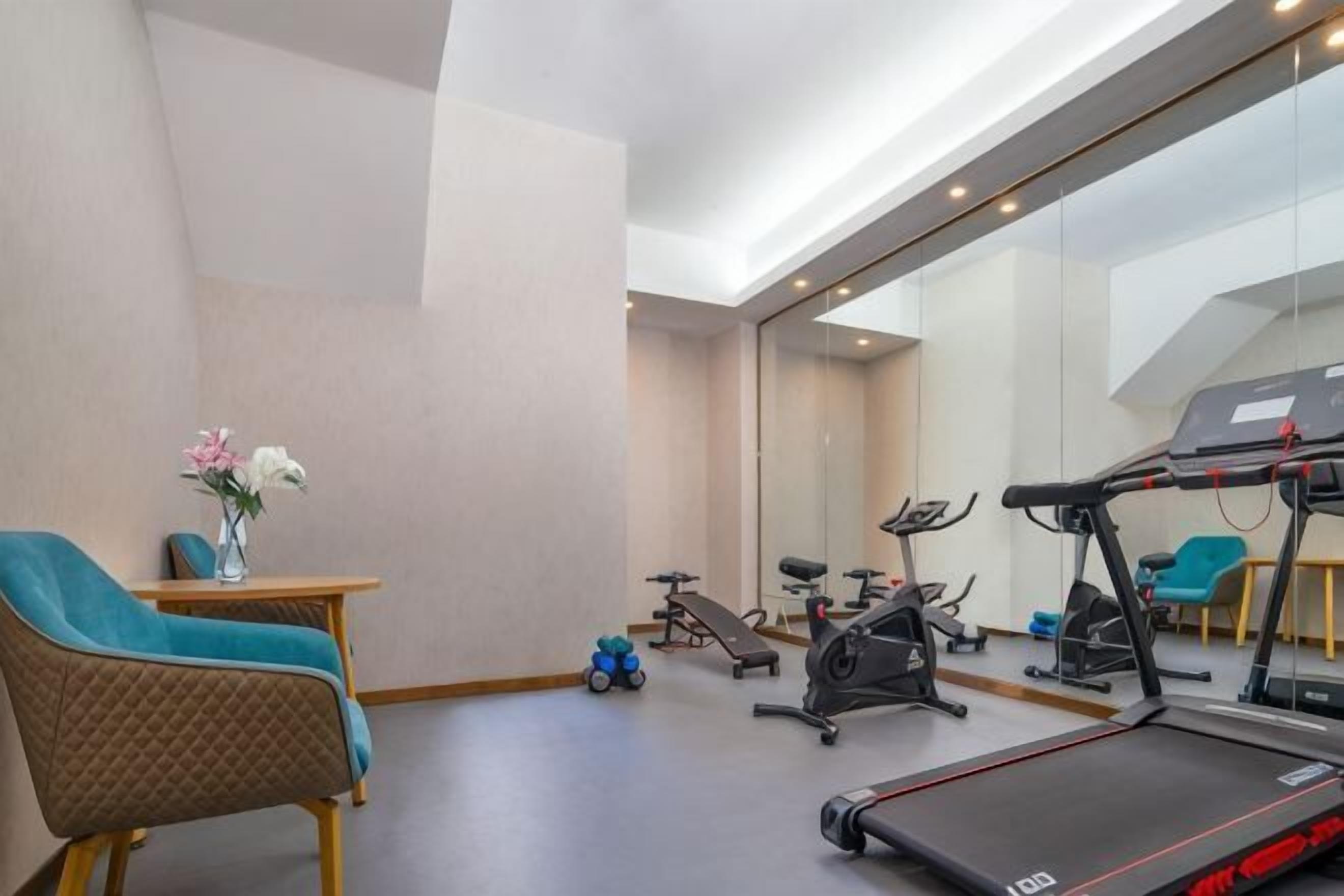 A room with a treadmill, exercise bike, and a mirrored wall.