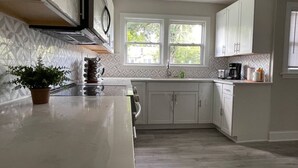 A modern kitchen with white cabinets, a marble countertop, and a window providing natural light. - Conveniently located spacious home (North Charleston)