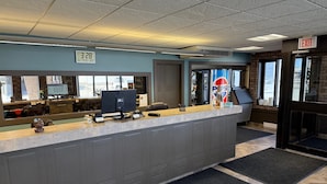 A reception area with a digital clock displaying 8:28, a large window with a view of the outside, and a Pepsi logo on the wall.