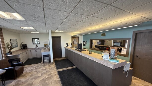 A reception area with a counter, seating, a coffee machine, and a clock displaying 3:28.