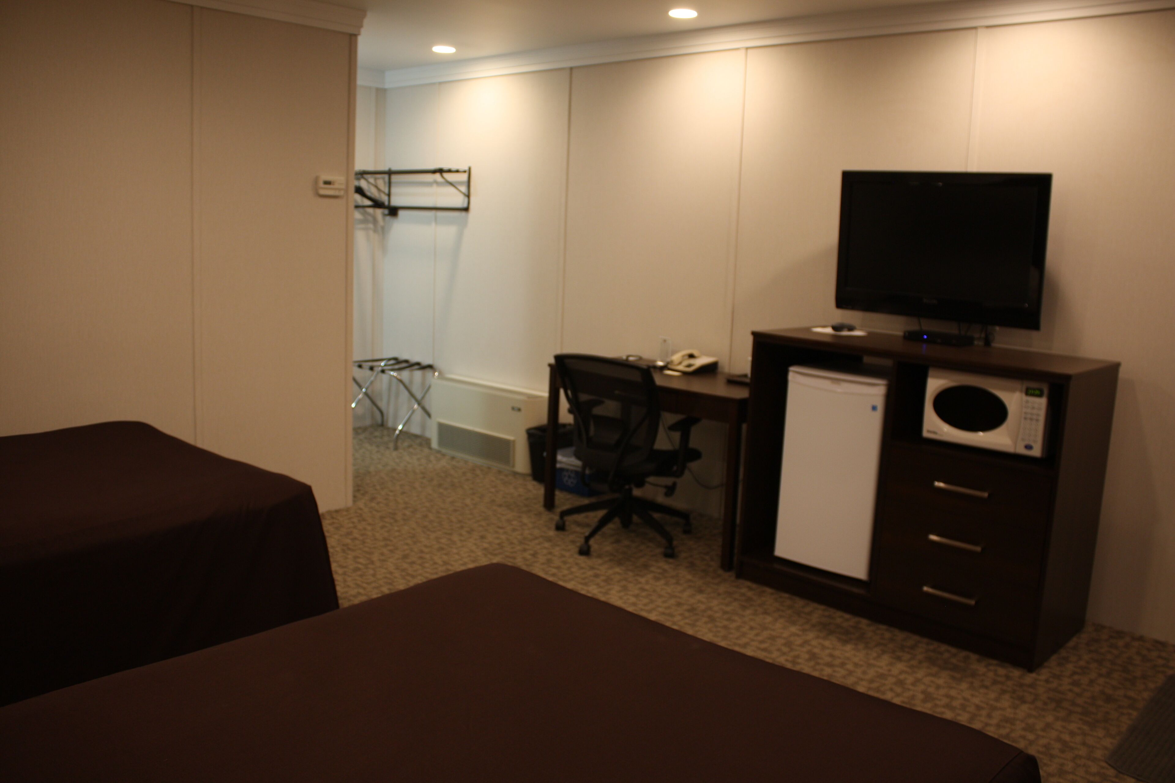 A hotel room with a bed, a desk with a computer, a television, and a microwave.