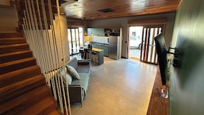 A spacious living area with a wooden staircase, a sofa, and a kitchen in the background. - VILLA PRIME BEACH (ARACAJU)