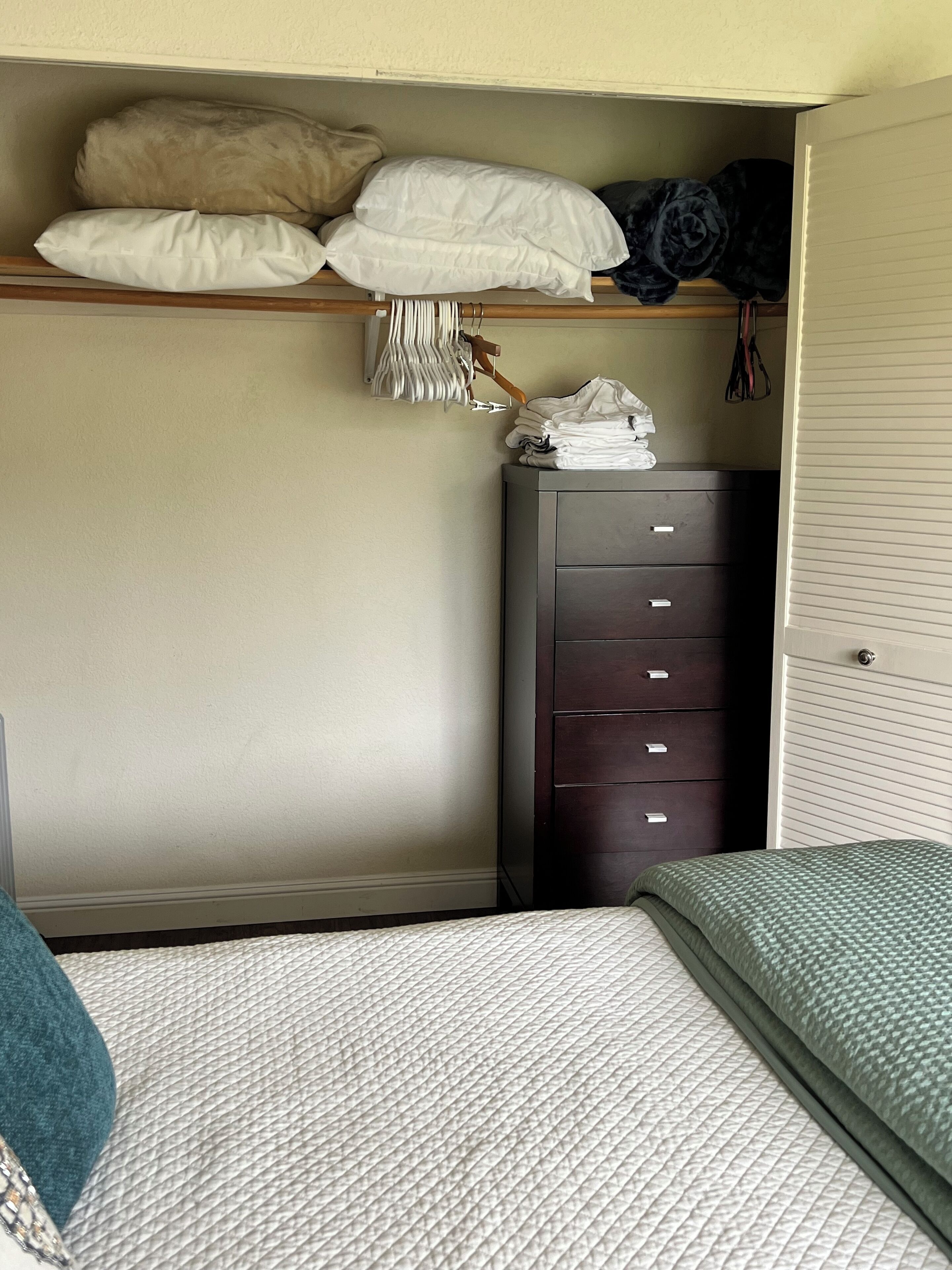 A bedroom with a bed, a dresser, and a closet.