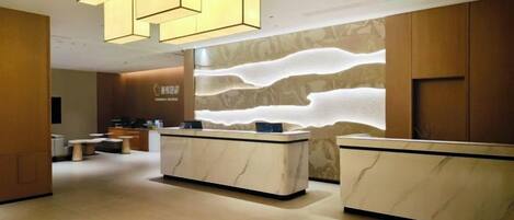 A reception area with a marble counter, wooden paneling, and a modern light fixture.