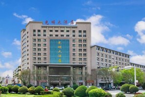 A multi-story building with a prominent blue sign and multiple windows. - Guangming Hotel (Jiuquan)