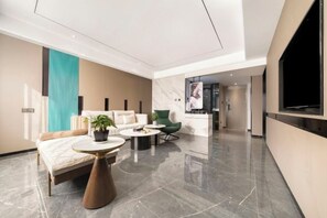 A modern hotel lobby with a sofa, coffee table, and chairs. - Guangming Hotel (Jiuquan)