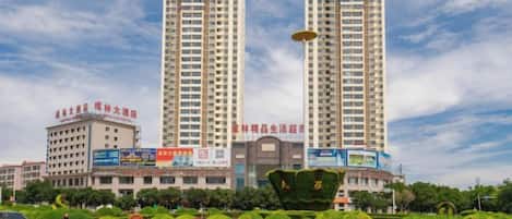 A modern building with two tall towers, surrounded by well-maintained greenery and a clear sky.