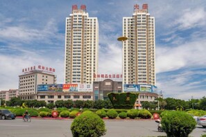 A modern building with two tall towers, surrounded by well-maintained greenery and a clear sky.