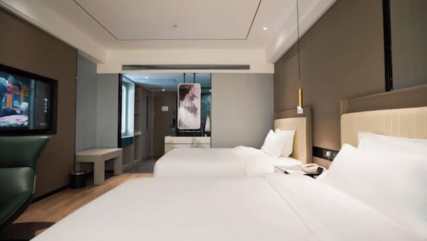 A modern hotel room with a large bed, a desk, a chair, and a TV. - Guangming Hotel (Jiuquan)
