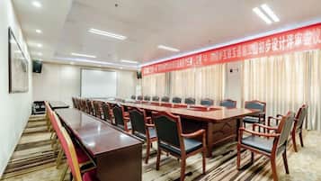 A conference room with a long table and chairs, a projector screen, and a banner.