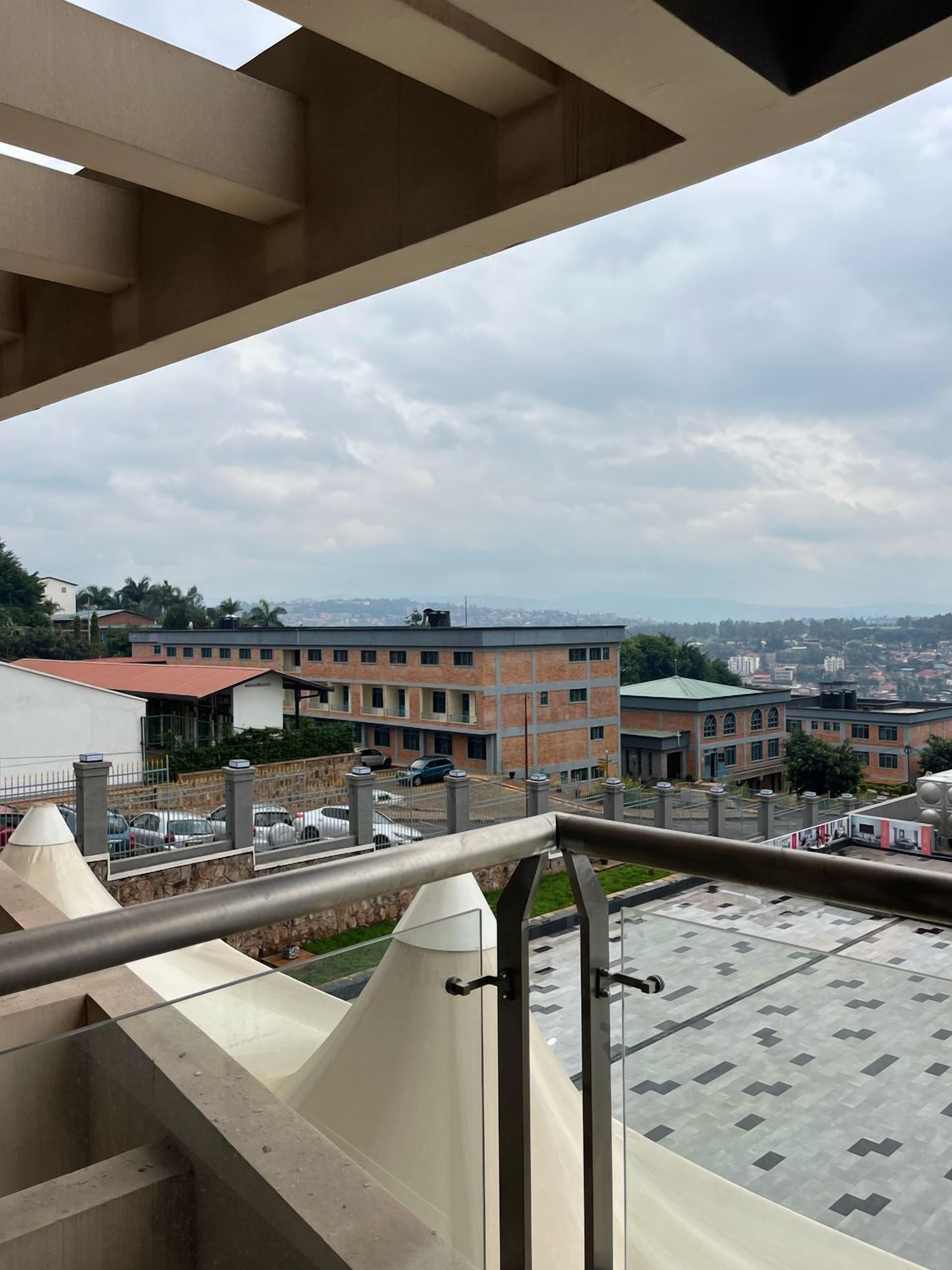 A balcony with a view of a parking lot and buildings in the background.