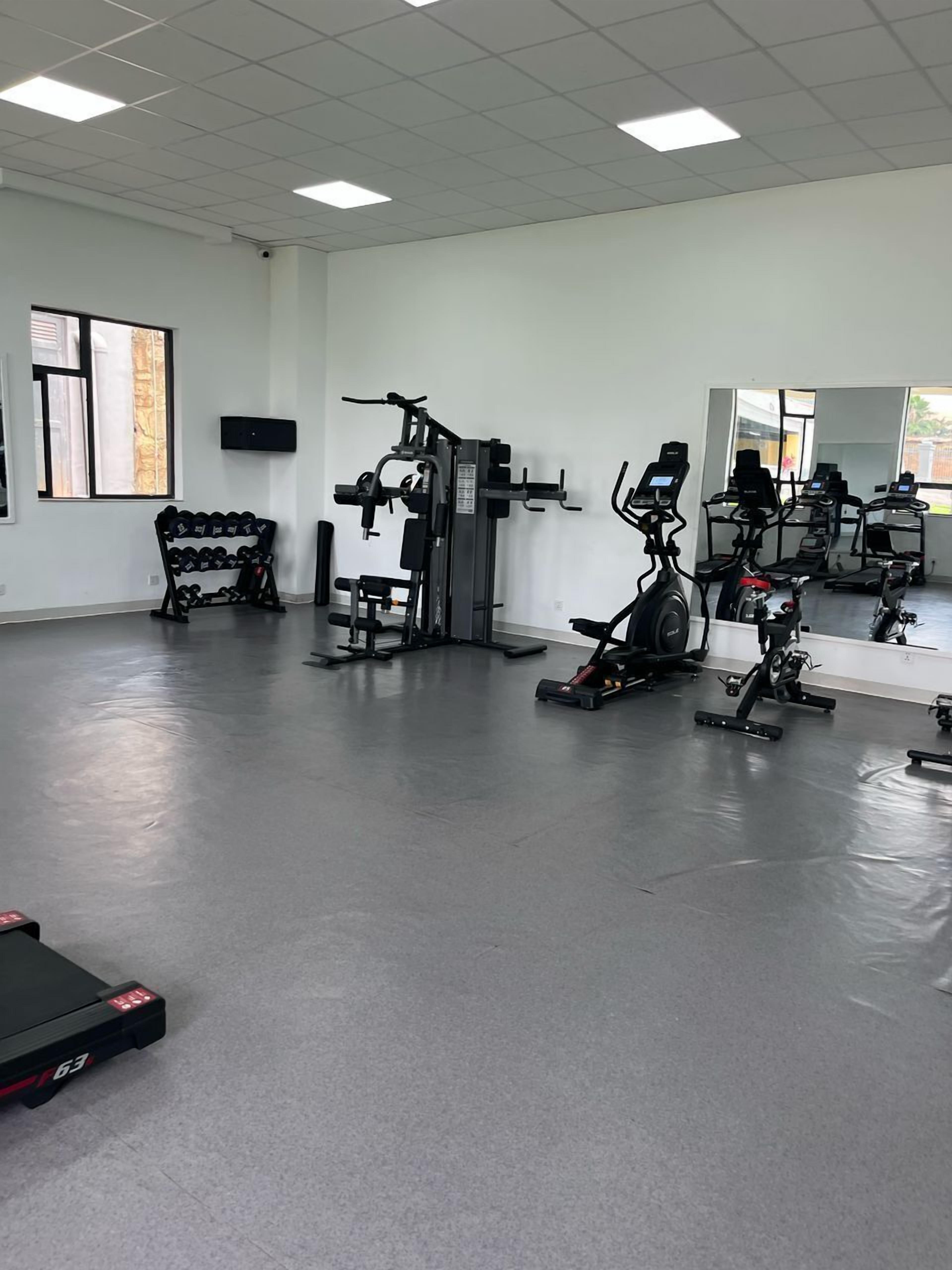Une salle de sport équipée de machines de cardio, de matériel de musculation et d’un porte-haltères.