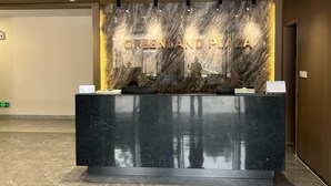 A reception desk with a marble wall and the text "GREENLAND PLAZA" above it. - Kigali Greenland Serviced Apartments (Kigali)