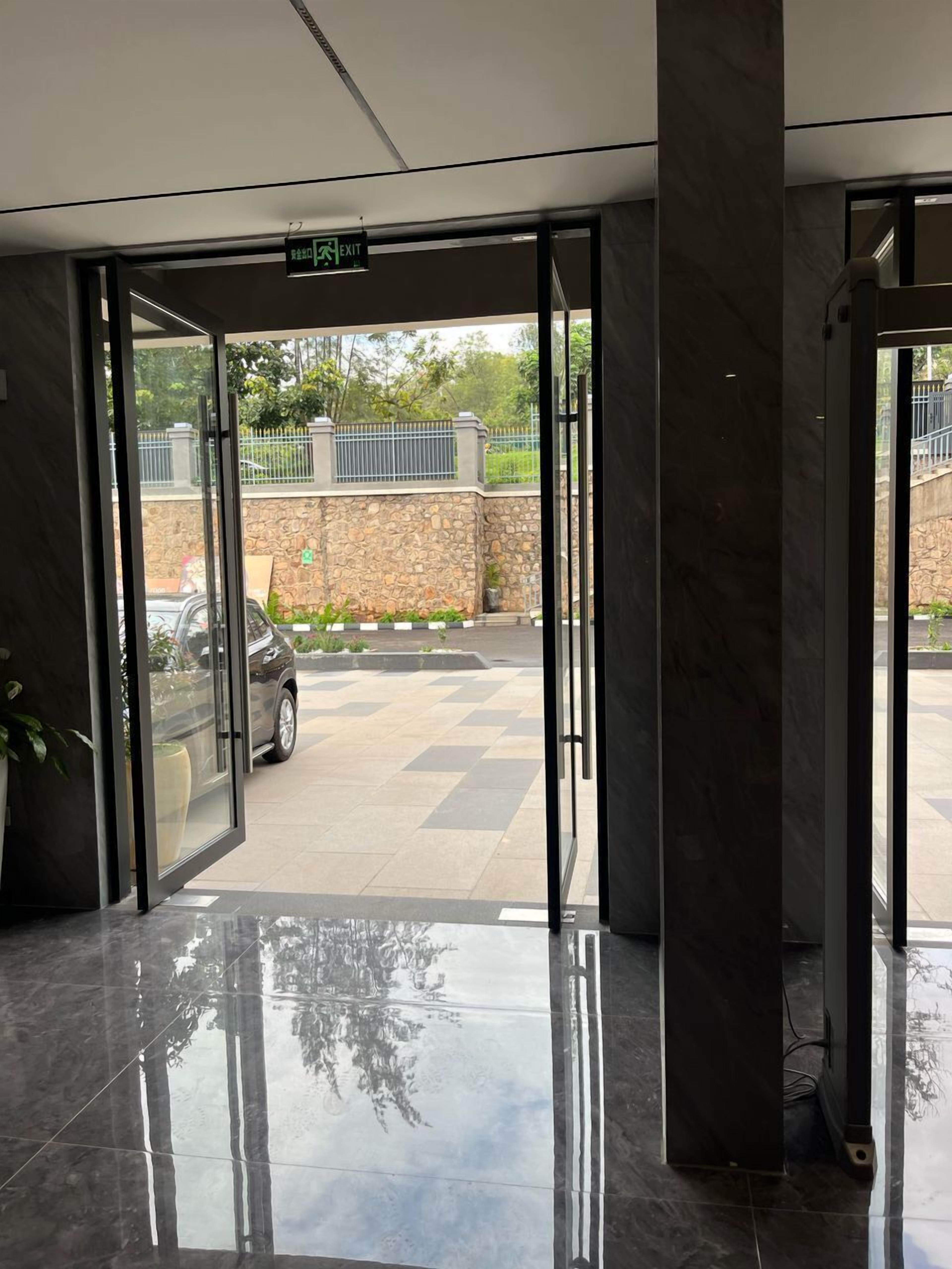 Une entrée moderne avec des portes en verre, un mur en pierre et une zone pavée à l’extérieur.