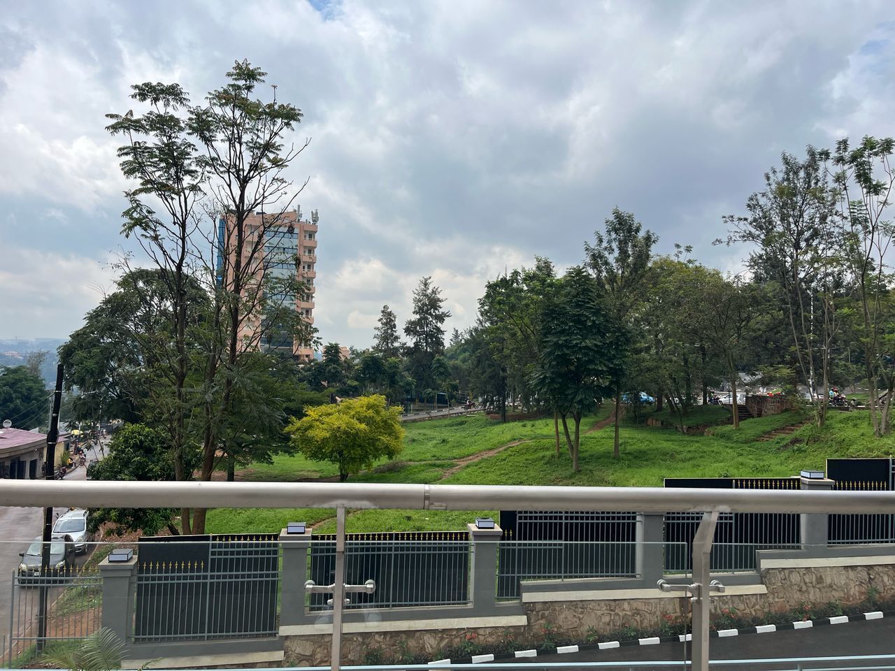 A view of a park with a pathway, trees, and a distant building.