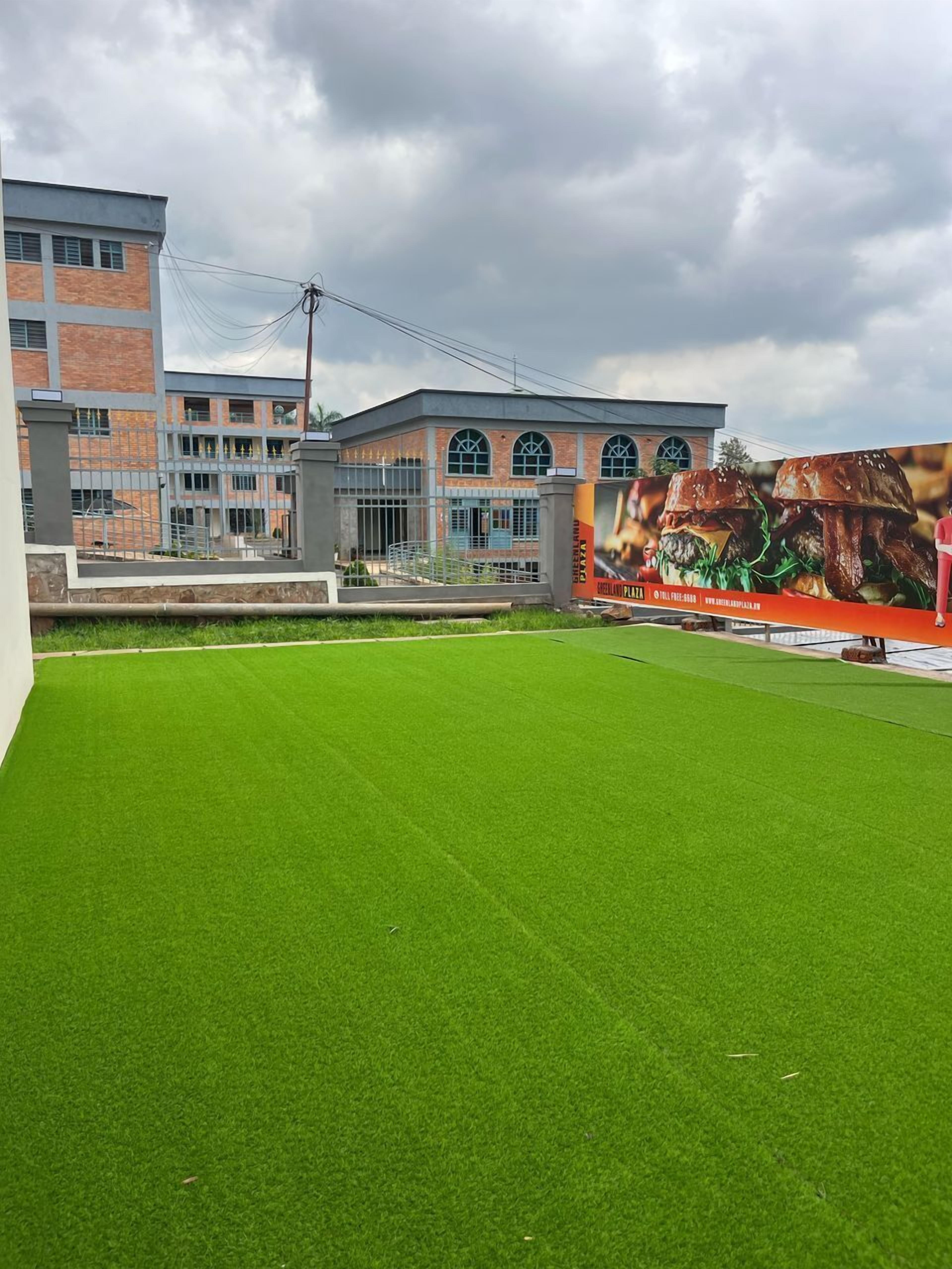 A building with a green artificial lawn in front, a mural on the side, and a brick facade.