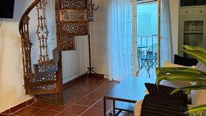 Ein Wohnzimmer mit Wendeltreppe, einem Sofa, einem Couchtisch und einem an der Wand befestigten Fernseher.
