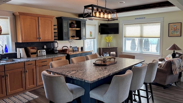 A modern kitchen with a central island, wooden cabinets, and a dining area with bar stools.