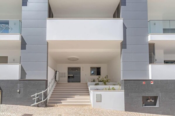 Un edificio moderno con una escalera central, techo plano y un balcón en el piso superior.
