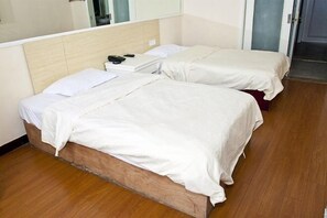 Een hotelkamer met twee bedden, een houten hoofdbord, een nachtkastje met een telefoon en een spiegel.