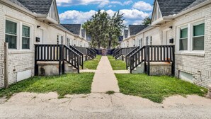 A row of white brick buildings with black railings and a central pathway leading to a tree. - Centrally Located Near Downtown W/ In Unit W&D! (Wichita)