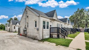 A single-story white building with a gabled roof, a front porch with a black railing, and a paved driveway. - Centrally Located Near Downtown W/ In Unit W&D! (Wichita)