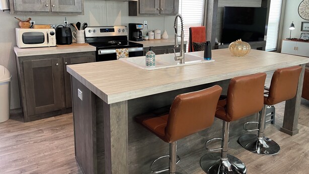 Una cocina moderna con armarios de madera oscura, electrodomésticos de acero inoxidable y una isla central con taburetes de bar.