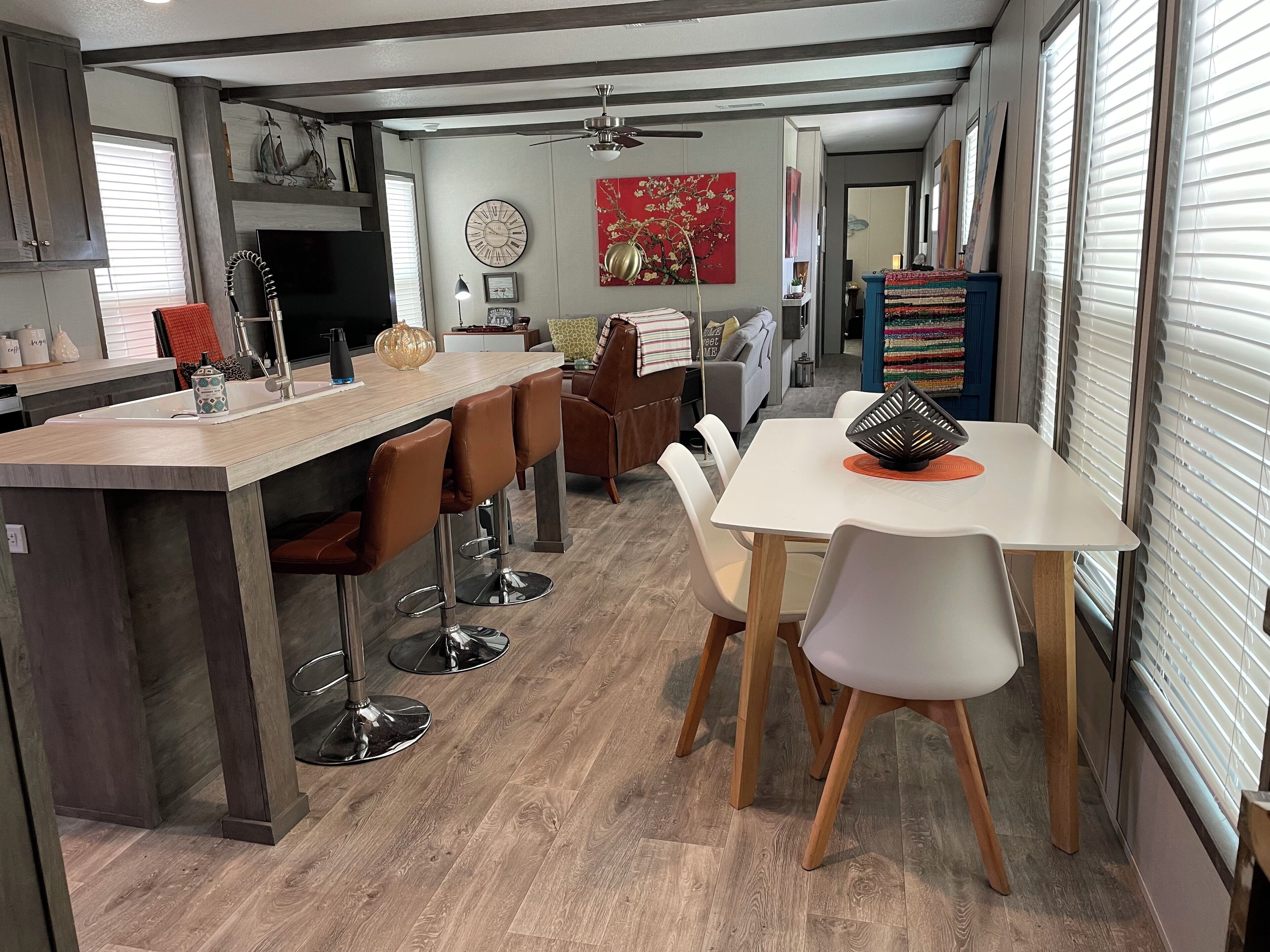 Una cocina moderna con una isla central, taburetes de bar y un comedor con mesa y sillas.