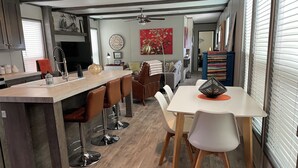 Una cocina moderna con una isla central, taburetes de bar y un comedor con mesa y sillas.