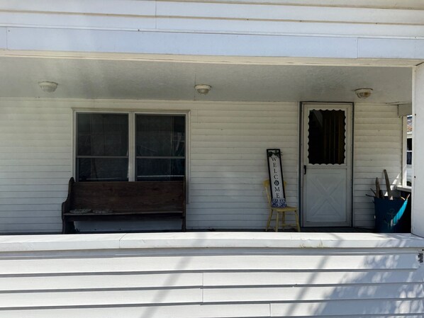 A porch with a bench, a welcome sign, and a door. - LAKE VIEW!!! Amazing sunsets! Charming 2-bedroom house in beautiful Conneaut. (Conneaut)