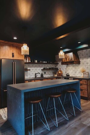 Une cuisine moderne dotée d’un bar, de meubles en bois et d’un crédence décorée.