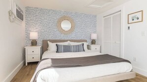 A bedroom with a bed, nightstands, a wall-mounted mirror, and a framed picture. - Ocean Boulevard South, 3 min walk to the beach! (Rye)
