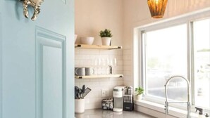 A kitchen with white cabinets, a sink, a window with a view, and a hanging light fixture. - Ocean Boulevard South, 3 min walk to the beach! (Rye)
