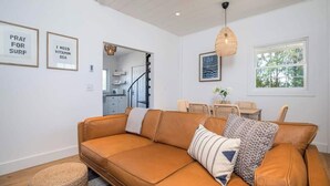 A modern living room with a leather sofa, a woven pouf, and a dining area with a table and chairs. - Ocean Boulevard South, 3 min walk to the beach! (Rye)