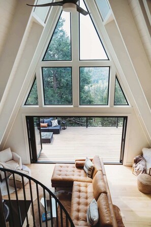 Um quarto no estilo loft com uma grande janela, um deck de madeira e um sofá.