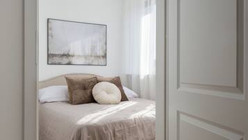 A bedroom with a bed, pillows, a wall-mounted artwork, and a door.