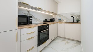 Een moderne keuken met witte kastjes, een zwarte oven en een marmeren achterwand.