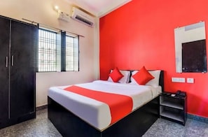 A hotel room with a bed, a wardrobe, a nightstand, and a red accent wall. - Spacious 6-bedroom house with WiFi, AC in enchanting Varanasi (Varanasi)