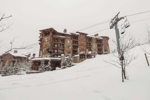 A multi-story hotel with a ski lift in the background.