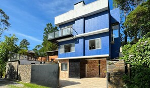 Una casa moderna de dos pisos con fachada de piedra y un balcón, y exterior azul.