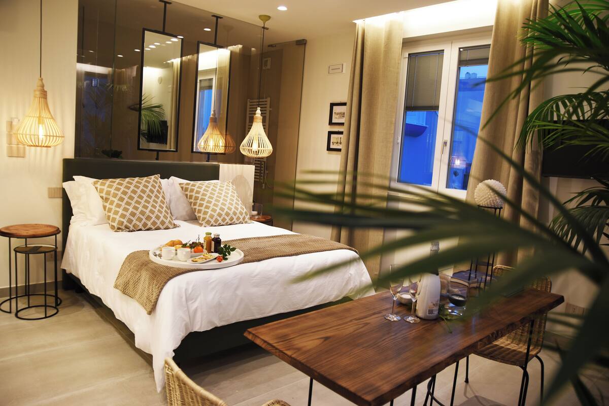 A hotel room with a bed, bedside table, and a dining table with chairs.