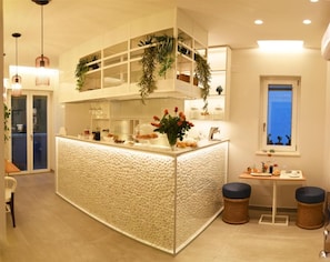 A modern kitchen with a central island, pendant lighting, and a window with a view. - B&B Dimora Vistamare (Barletta)