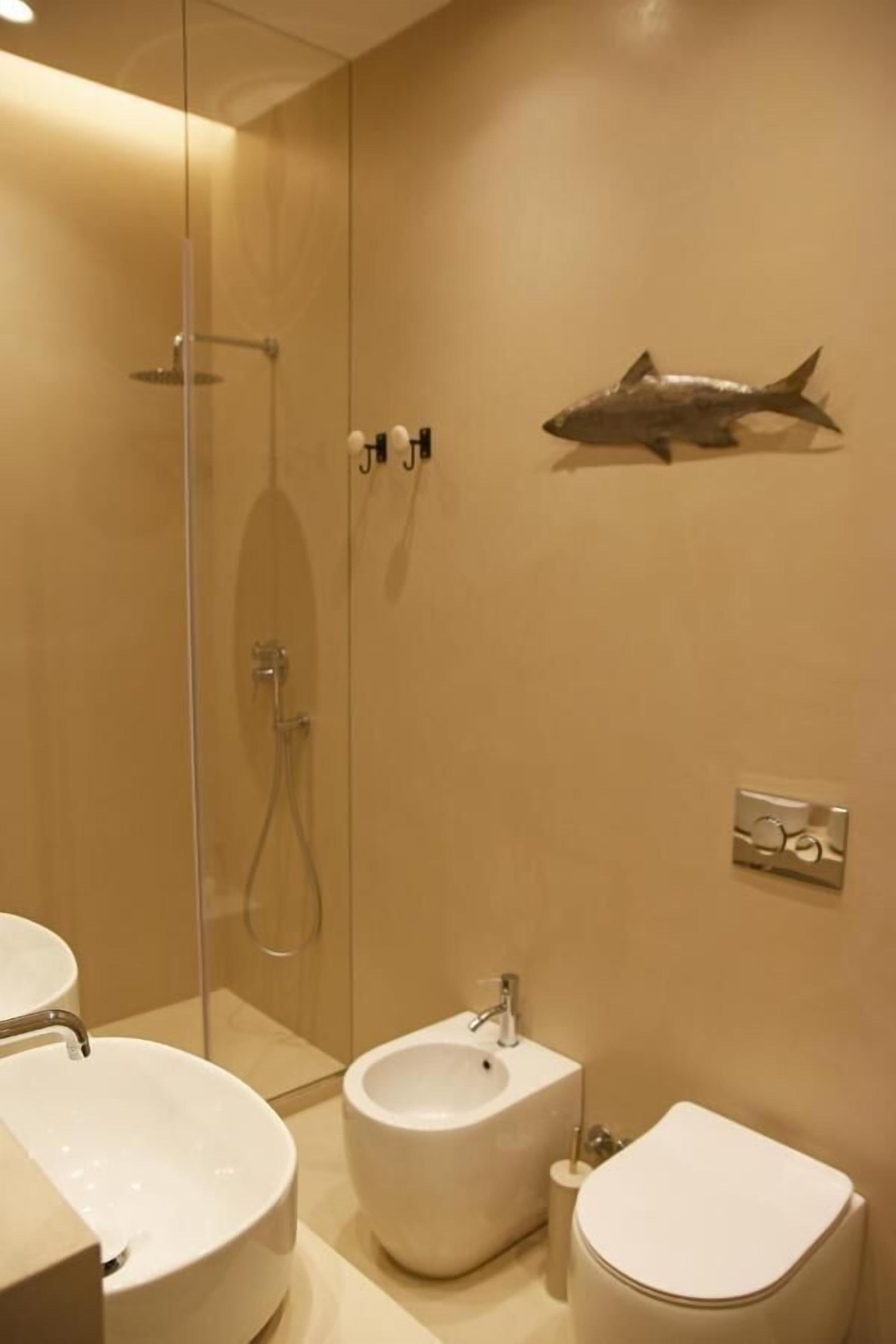 Een badkamer met een douchecabine, een bidet, een toilet en een wastafel.