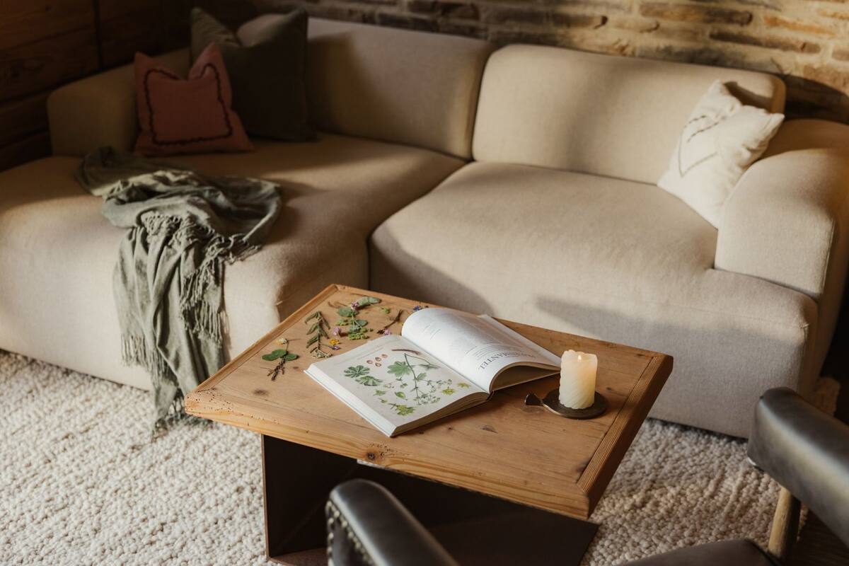 A cozy living room with a wooden coffee table, a book, and a candle.