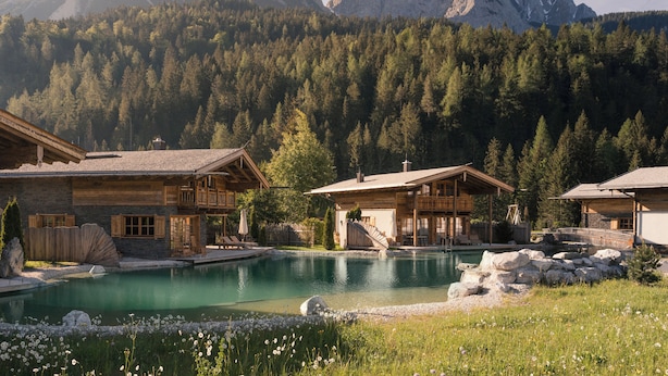 Un chalet de montagne doté d’une piscine, de cabanes en bois et entouré d’une forêt.